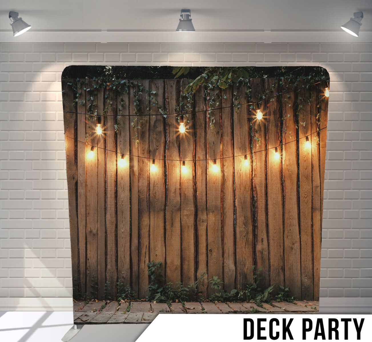 Wood fence backdrop with hanging string lights and ivy creating an outdoor party atmosphere.