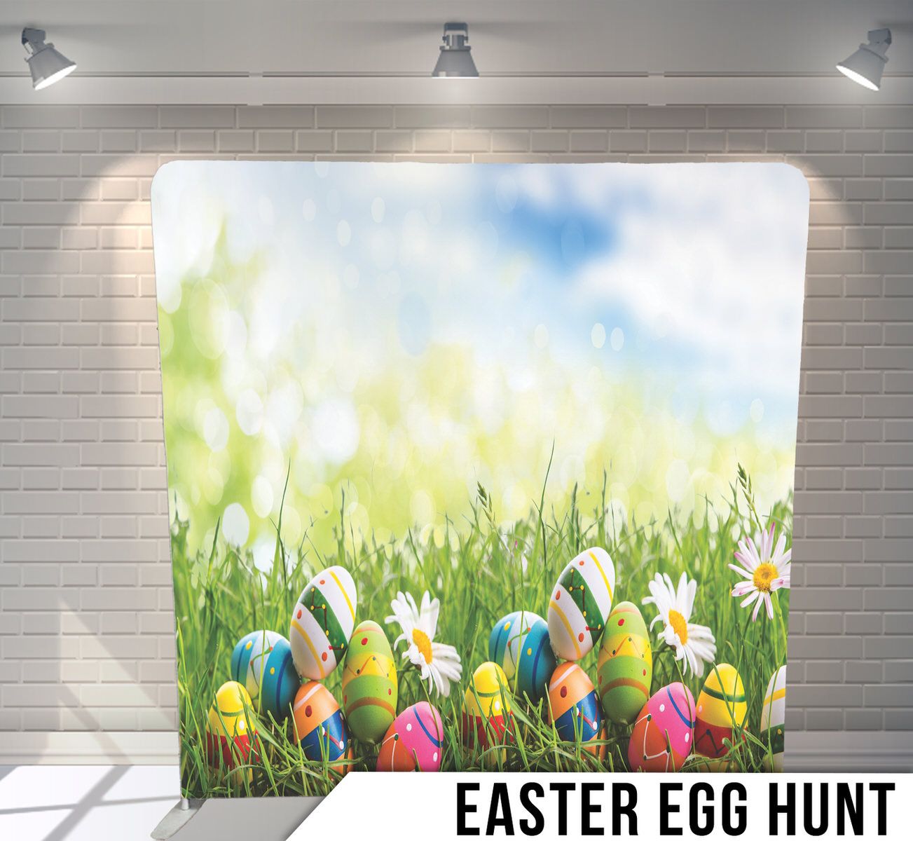Easter scene backdrop with colorful eggs nestled in grass and daisies under blue sky.