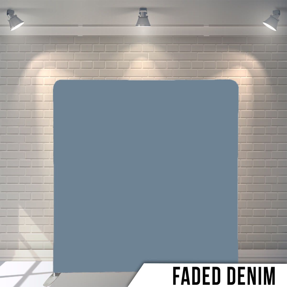 Professional photo backdrop setup showing faded denim-colored background with studio lighting against white brick wall.