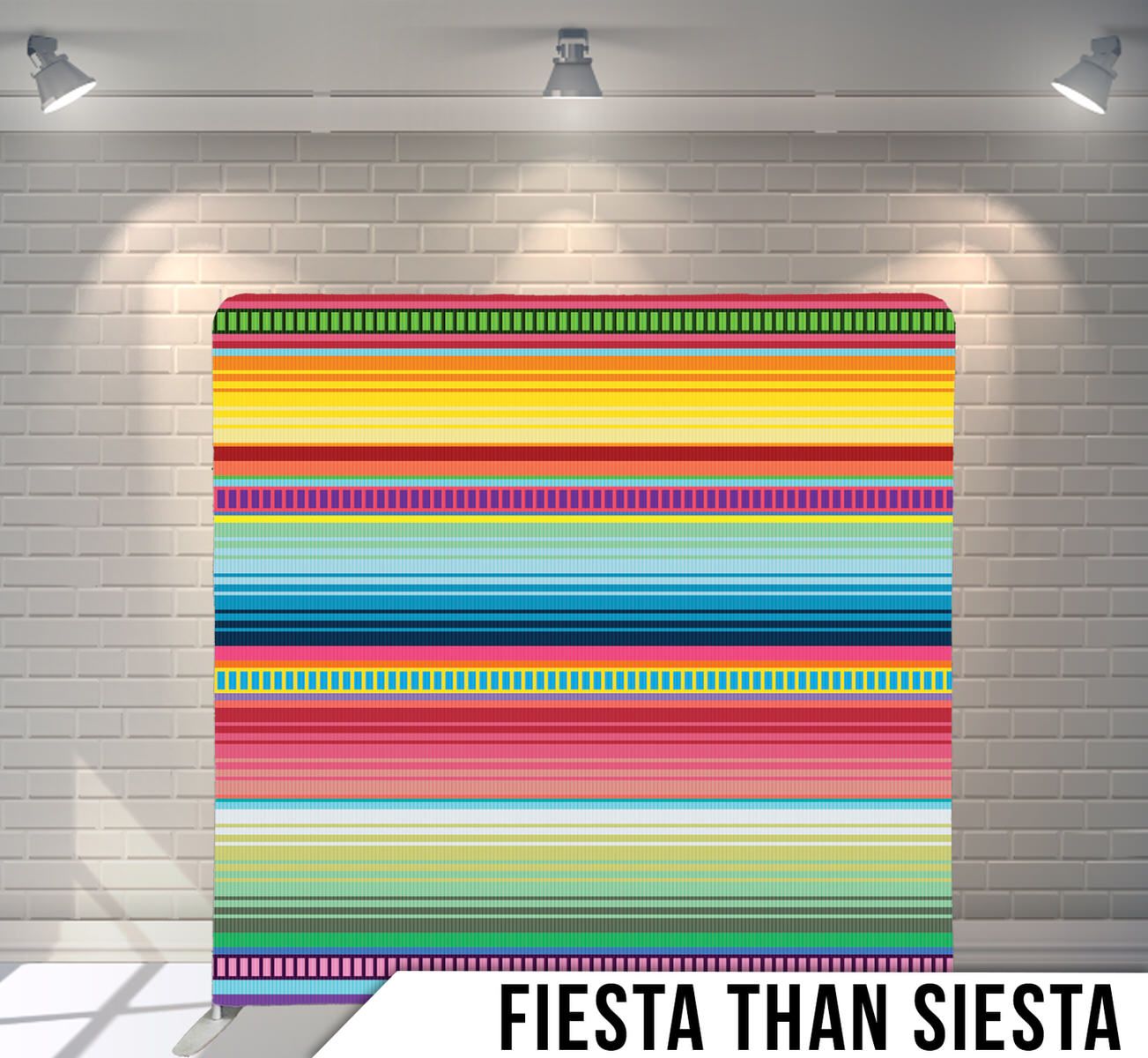 A colorful striped Fiesta party backdrop with traditional Mexican serape pattern design hanging on a white brick wall.