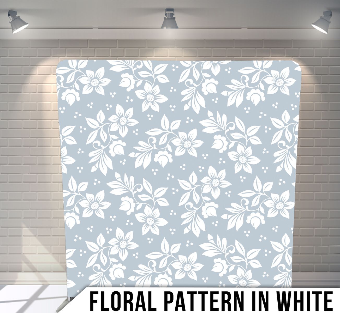 White floral pattern on a light gray seamless background displayed on a studio backdrop with spotlights.