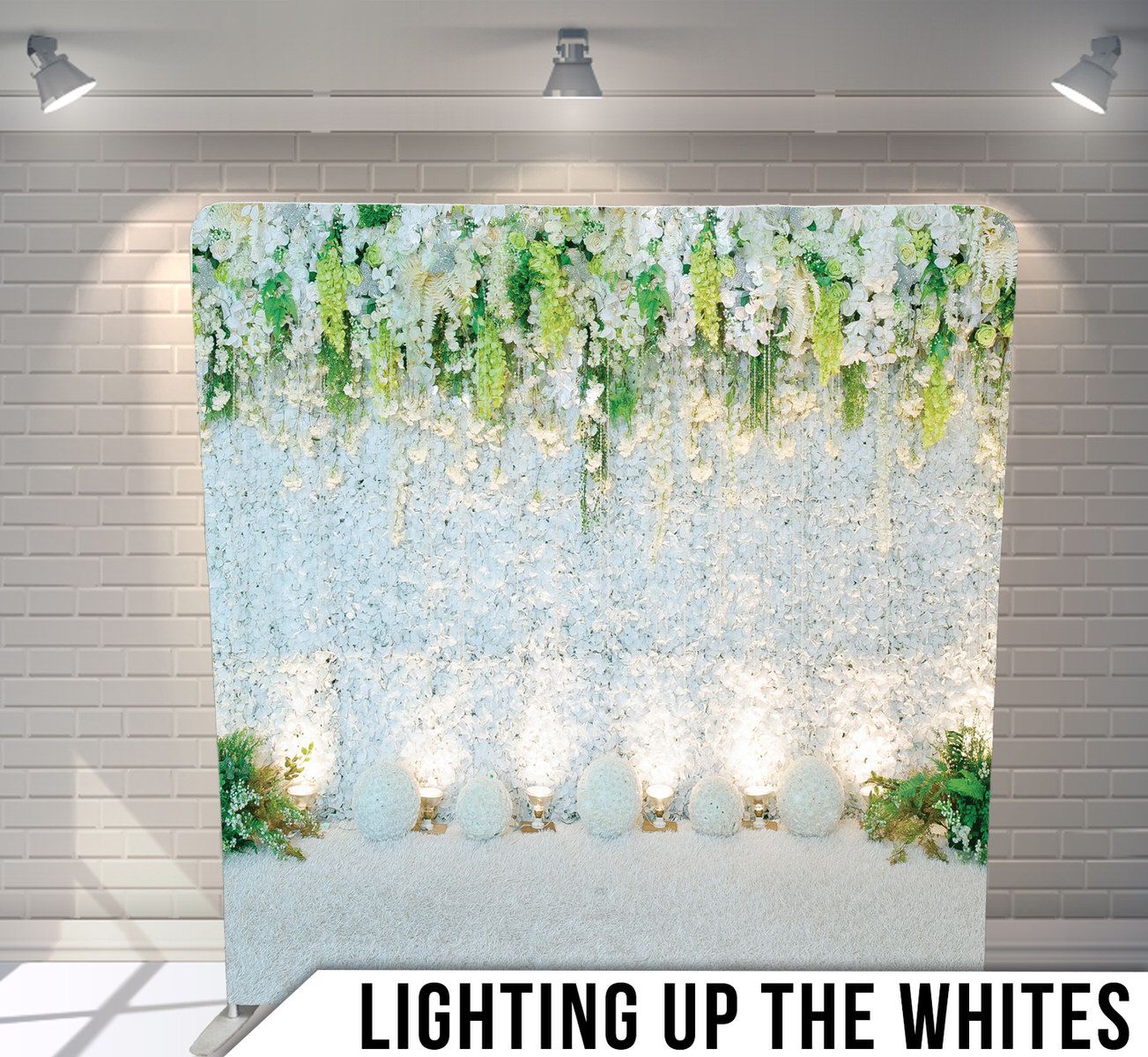 White floral backdrop with hanging greenery and string lights creating an elegant wedding photo setting.