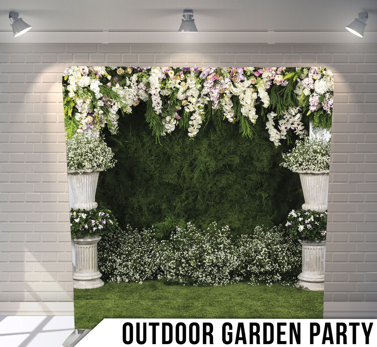 Garden party backdrop with white floral arrangements on pillars and green hedge wall.