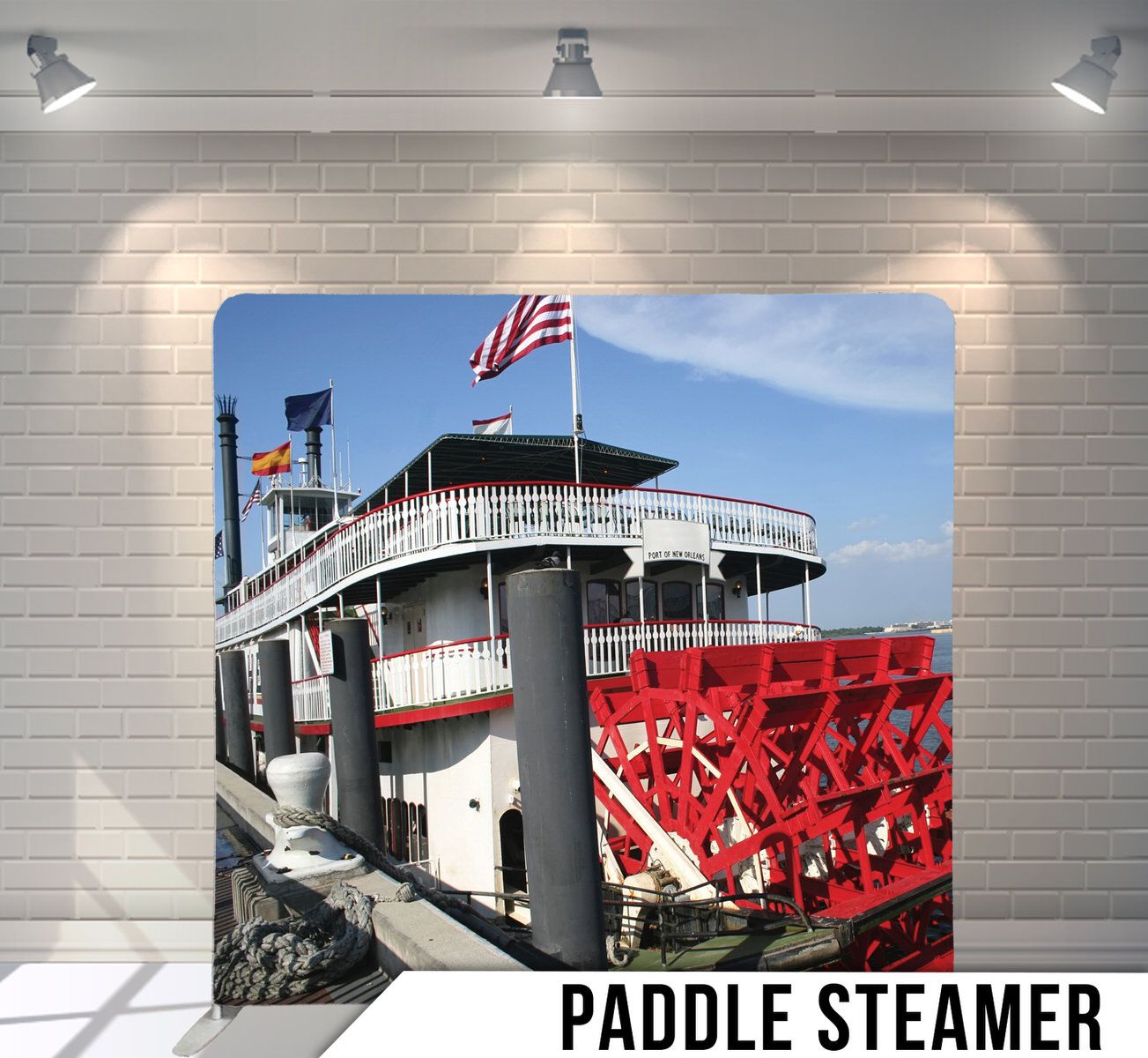 Vintage paddle steamer riverboat with red paddlewheel and American flag on display.