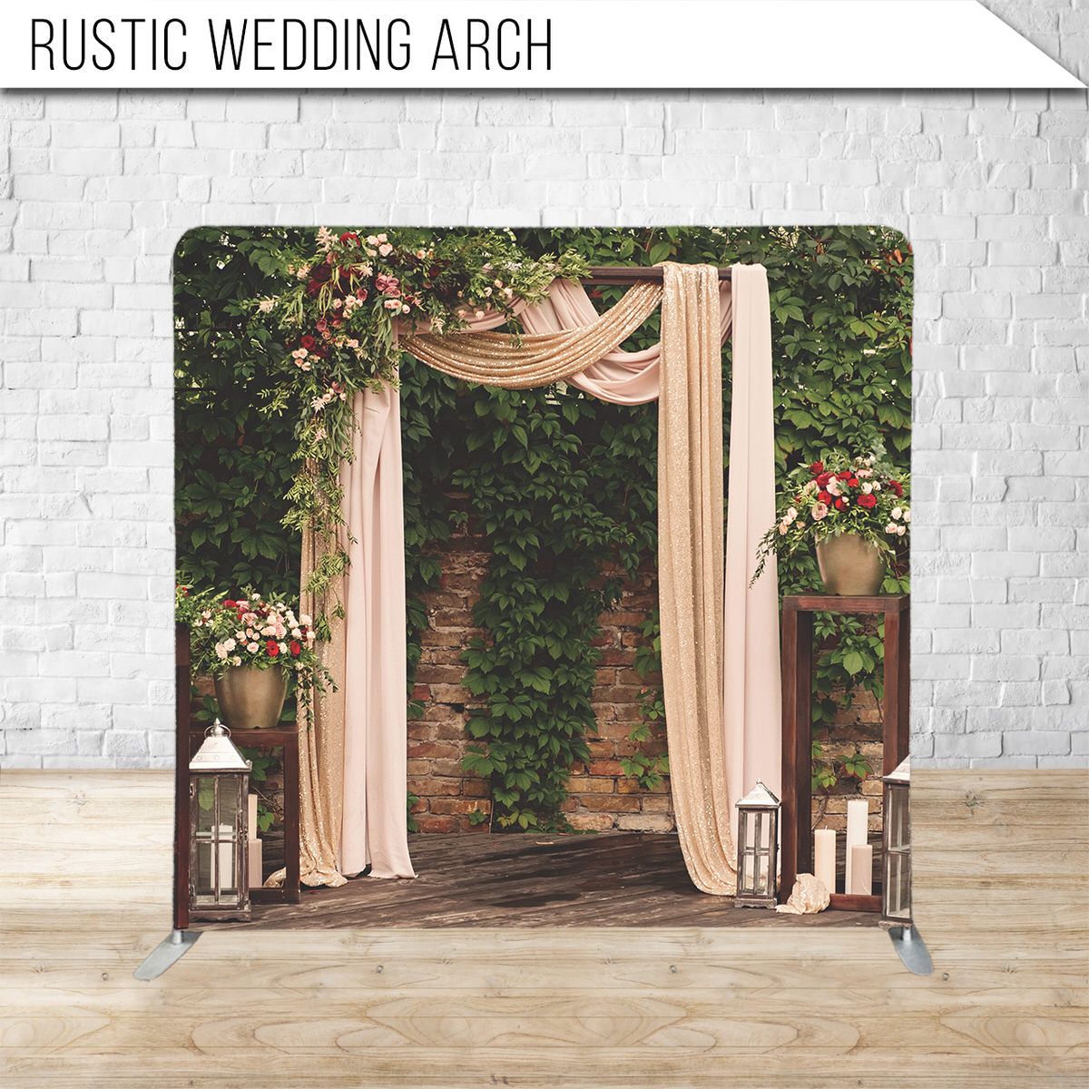 Elegant wedding arch with flowing blush fabric and floral arrangements against brick wall.