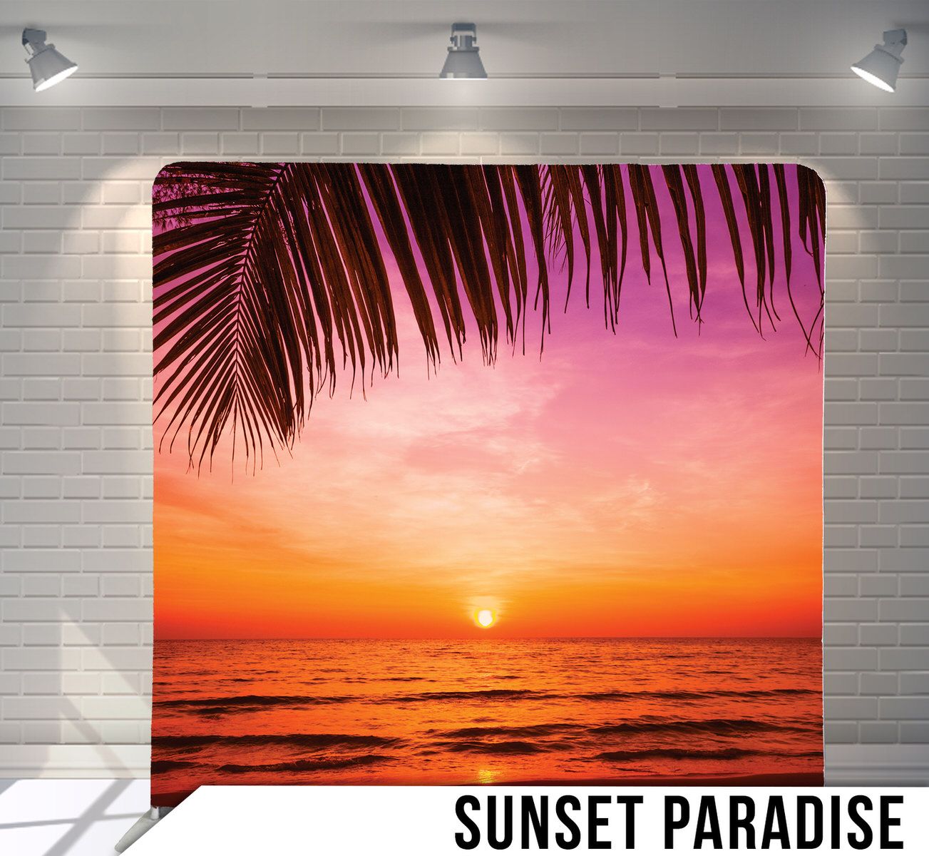 Tropical beach sunset with orange sky and palm frond silhouette framing the horizon.