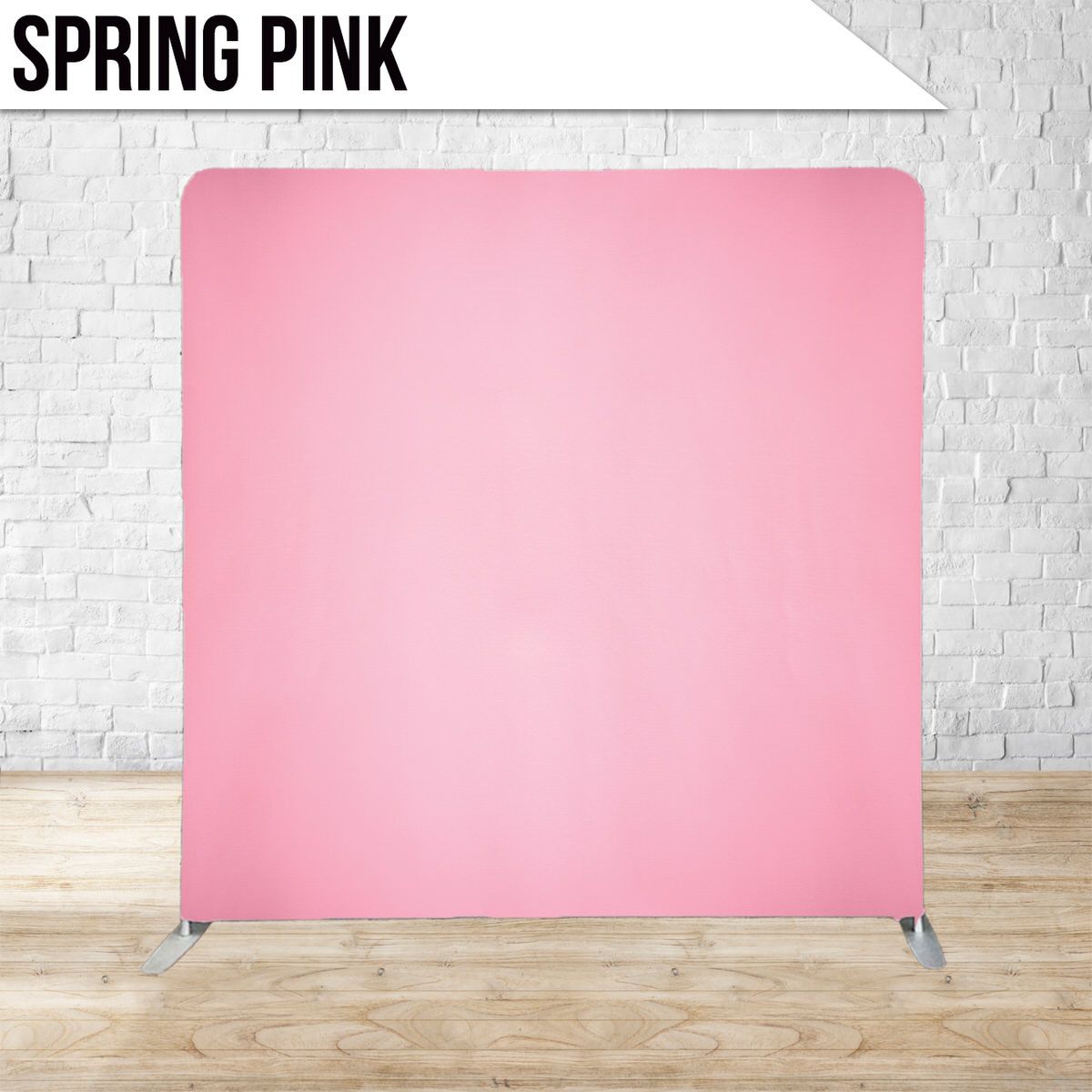 Solid pink photography backdrop displayed against white brick wall and wooden floor.