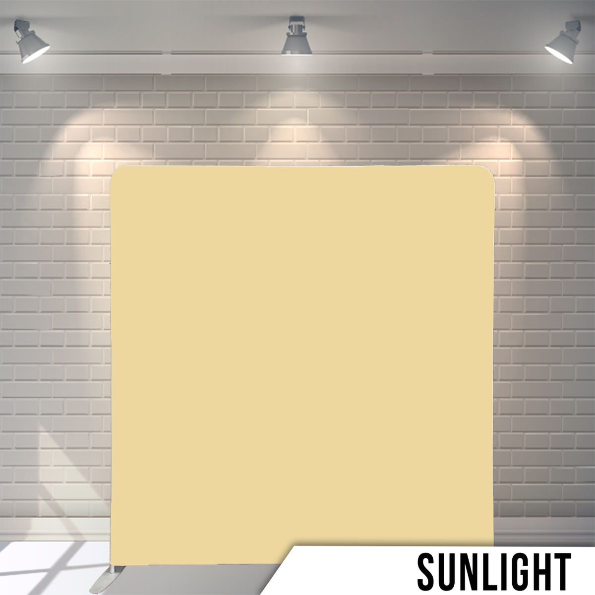 Solid cream colored backdrop against a brick wall with studio lighting.