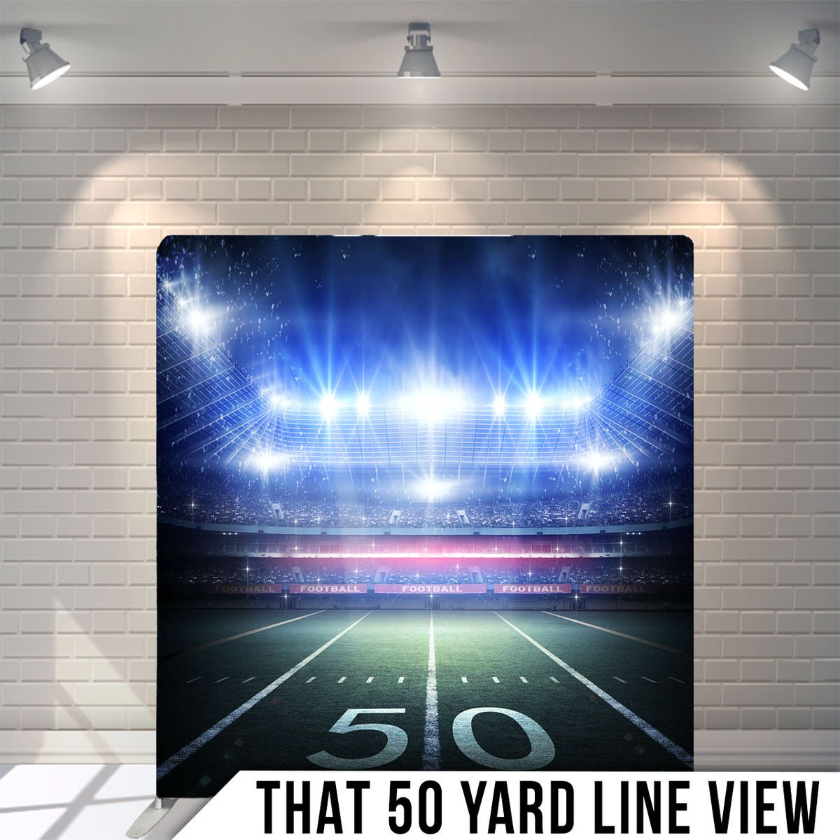 Football stadium at night with bright floodlights illuminating the 50 yard line.