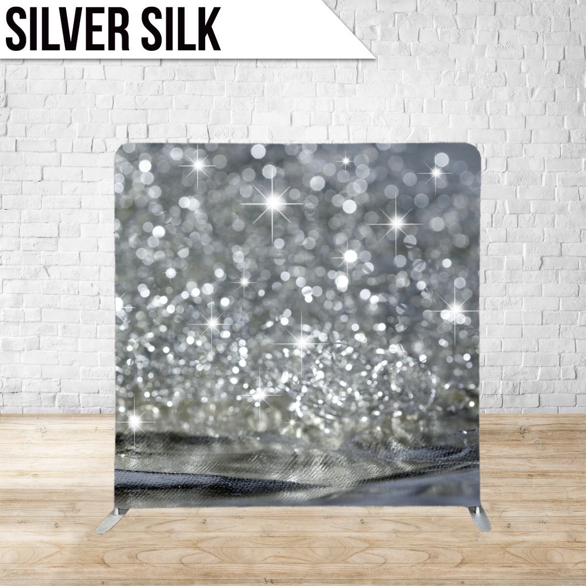 Shimmering silver silk backdrop with bokeh effect lighting against a white wall.