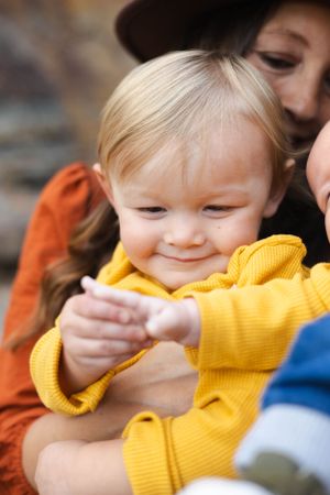 Close-up of young child in yellow sweater smiling and playing.