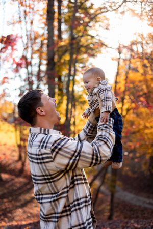 A tender moment captured in autumn forest with warm golden sunlight filtering through colorful fall foliage.