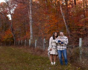 Couple poses with children against backdrop of vibrant fall foliage.