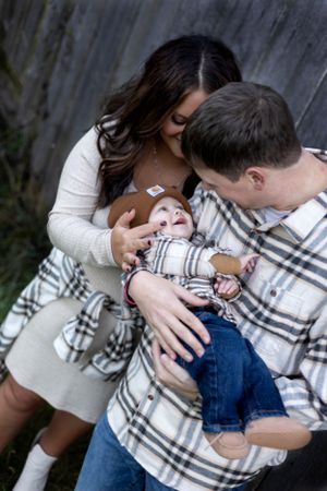 Parents sharing tender moment with baby wrapped in plaid blanket.