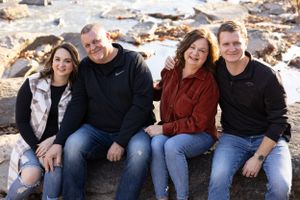 Group of four sitting together outdoors on rocky terrain wearing casual clothes.