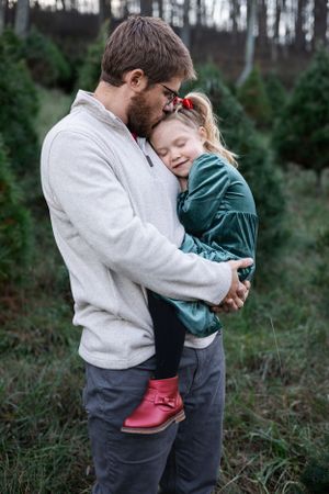Tender moment between parent and child in casual wear outdoors.