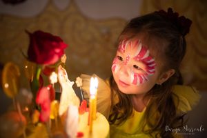 Close up of birthday celebration with candles and face paint glowing in golden candlelight.