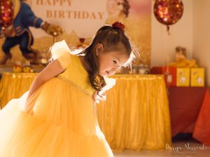 Elegant side profile of yellow dress movement against golden birthday party backdrop.