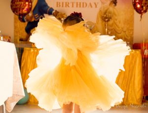 Yellow tulle party dress with flowing layers displayed at a birthday celebration with balloons.
