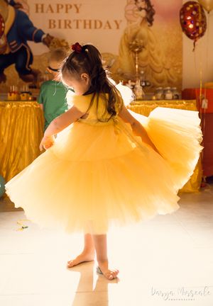 Spinning motion captured of yellow tulle dress during birthday party dance moment.