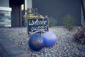 Welcome sign with blue balloons on stone pathway setting for party entrance.