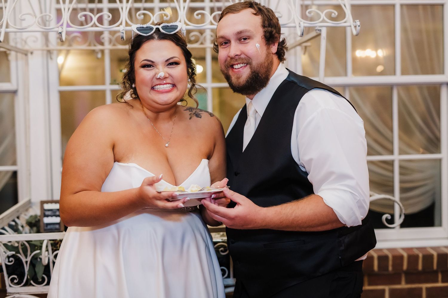 Newlywed couple shares a joyful moment during cake cutting at their wedding reception.