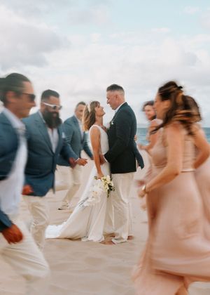 Wedding party in pastel colors celebrating on a beach at sunset.