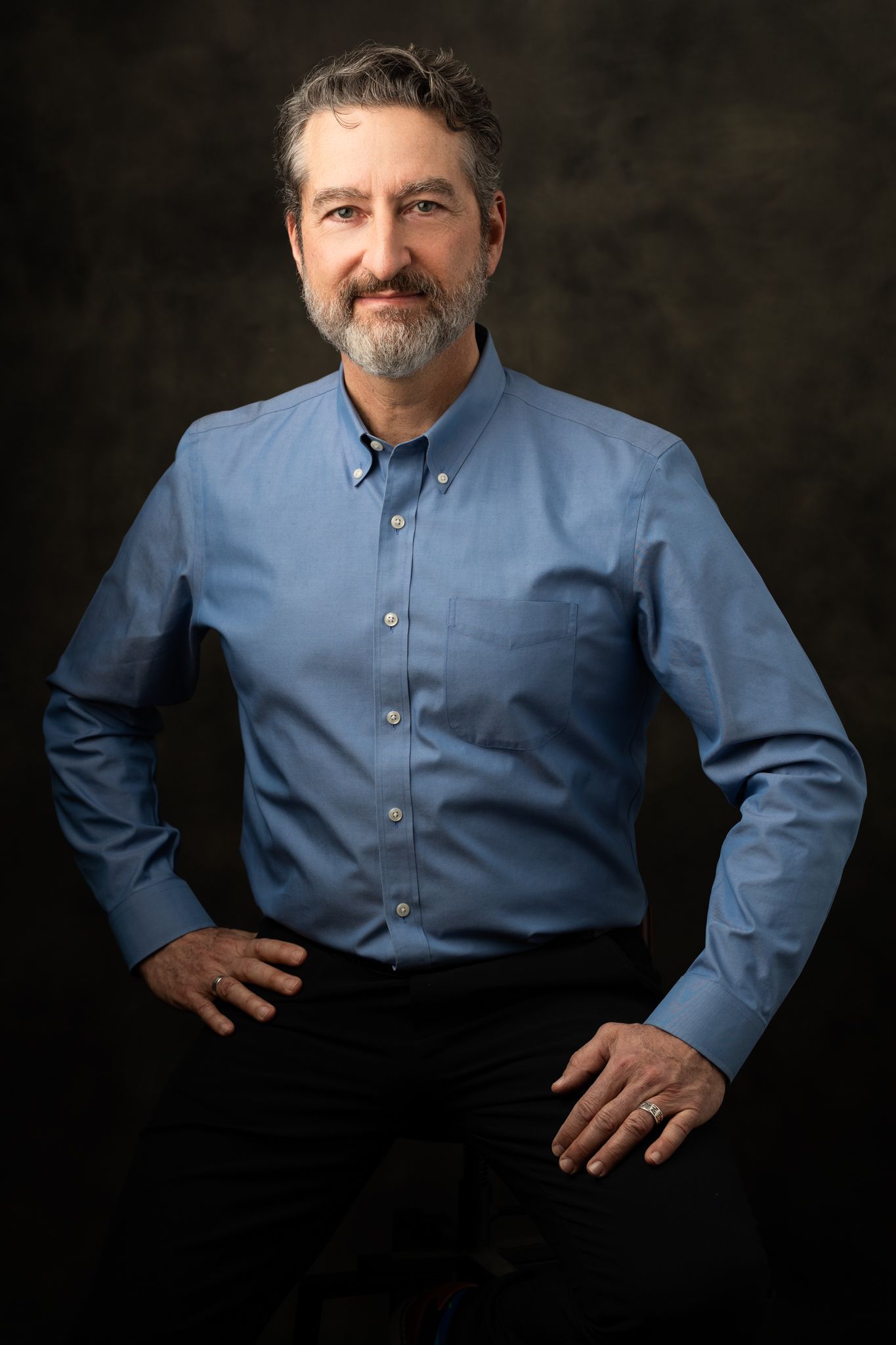 Professional headshot portrait against dark background.