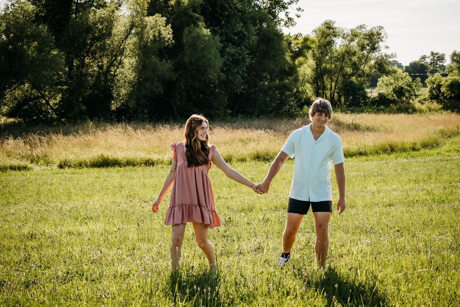 Couple holding hands while walking through field