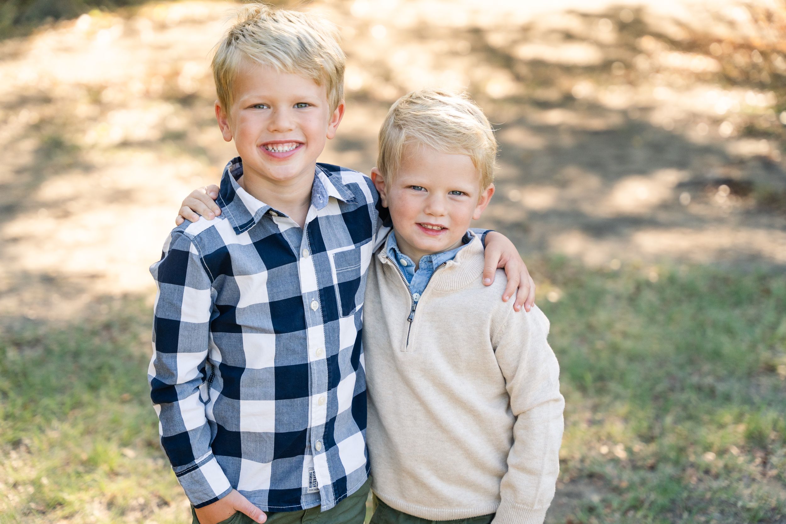 Family Session in Keller, Texas. Two boys wear neutral fall colors and give each other a side hug while smiling.