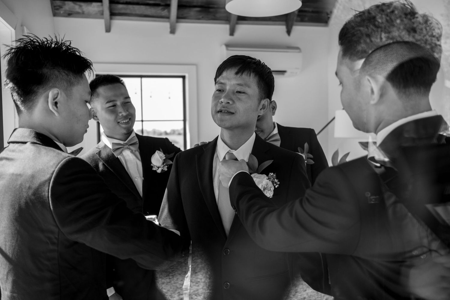 Black and white photo of groom and groomsmen laughing together during wedding preparations.