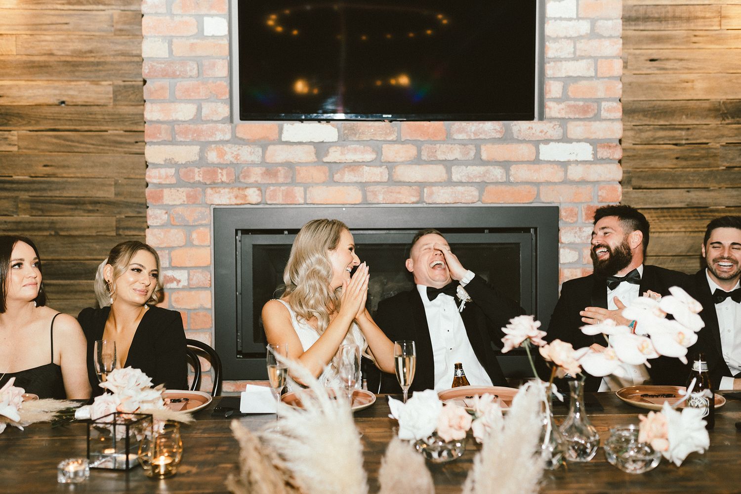 Wedding reception tables decorated with pink floral arrangements against exposed brick walls.