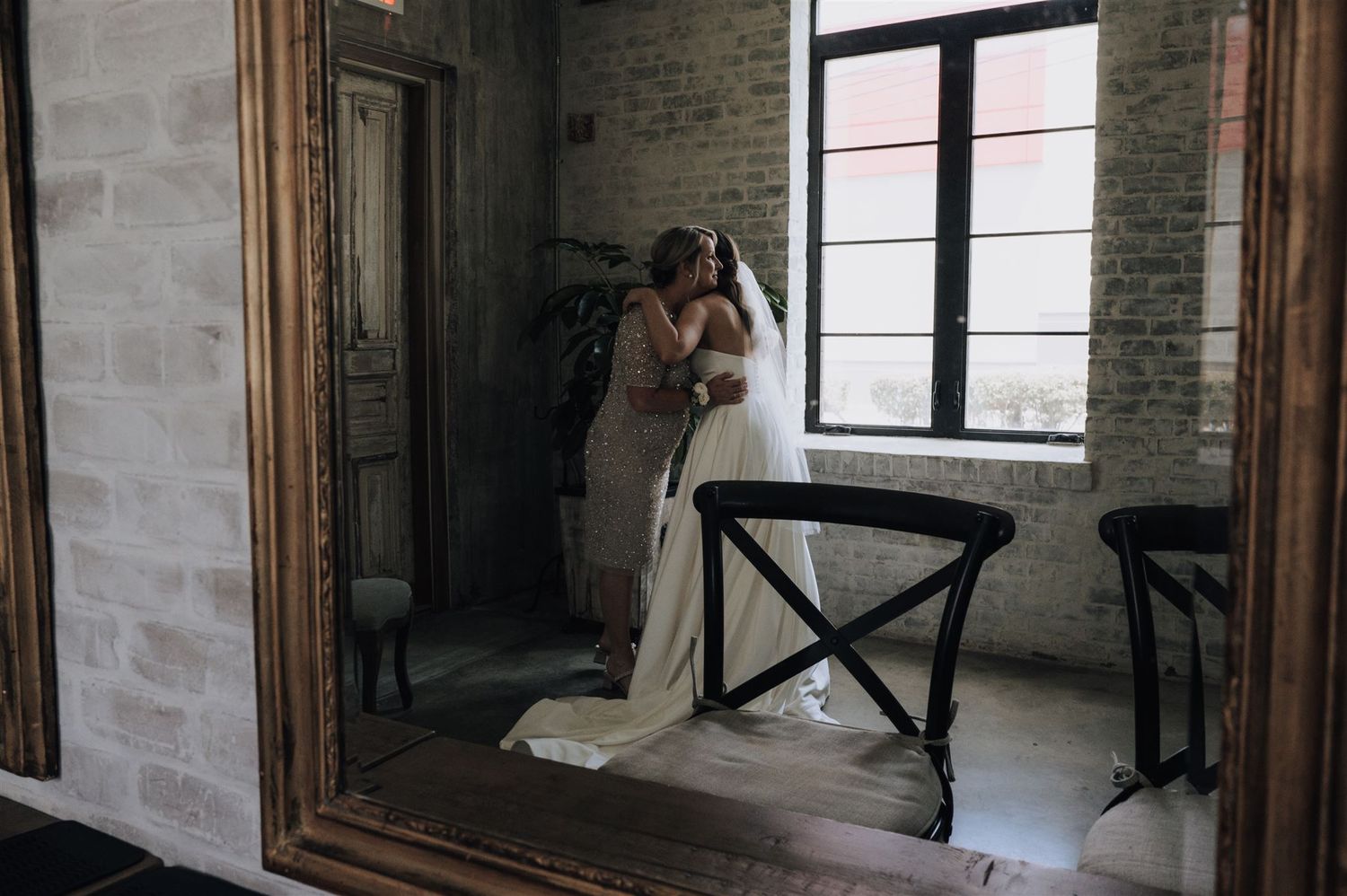 Reflection in mirror shows elegant wedding dress in an industrial chic venue.