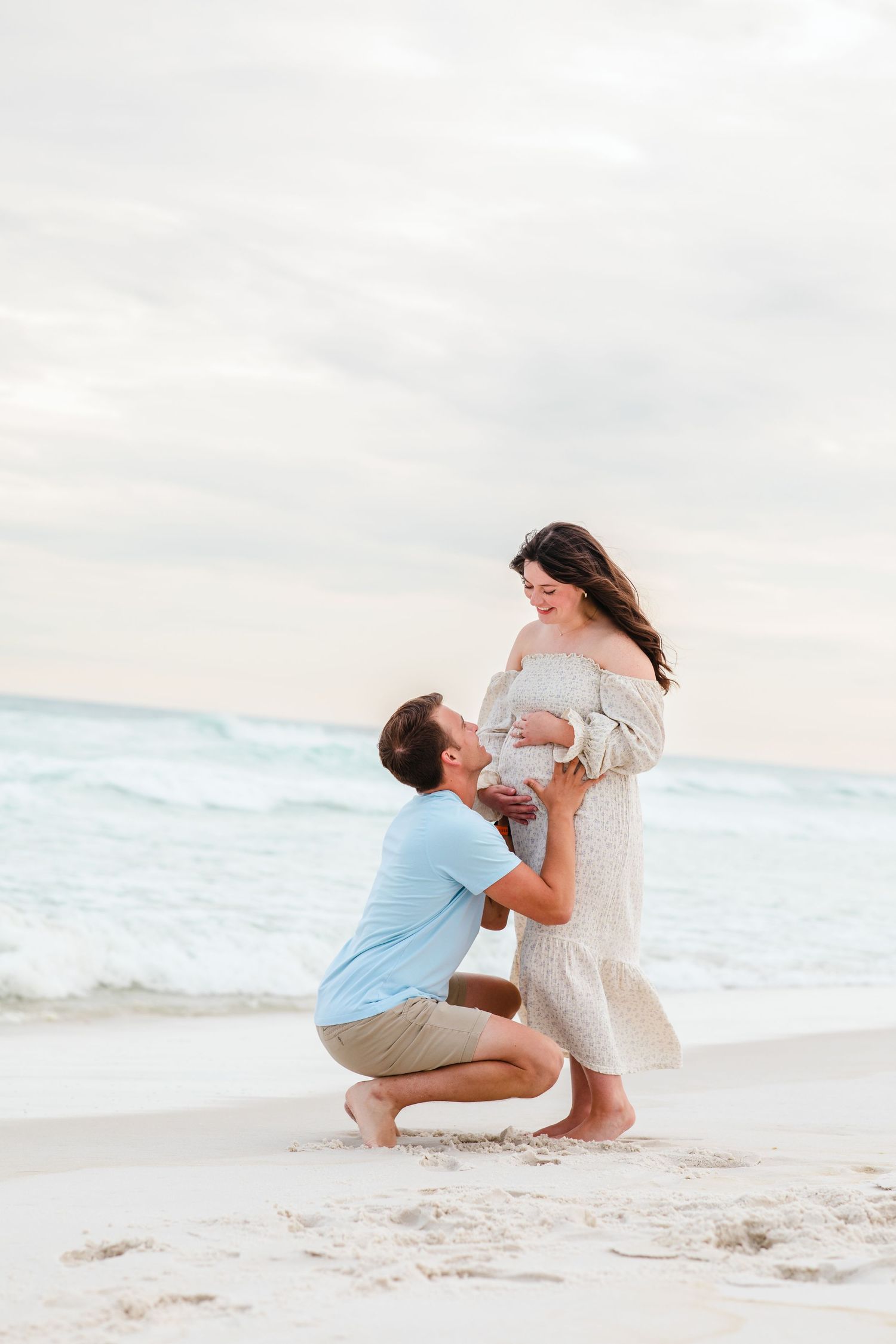 A heartwarming maternity photo showing affection on a beautiful beach setting.
