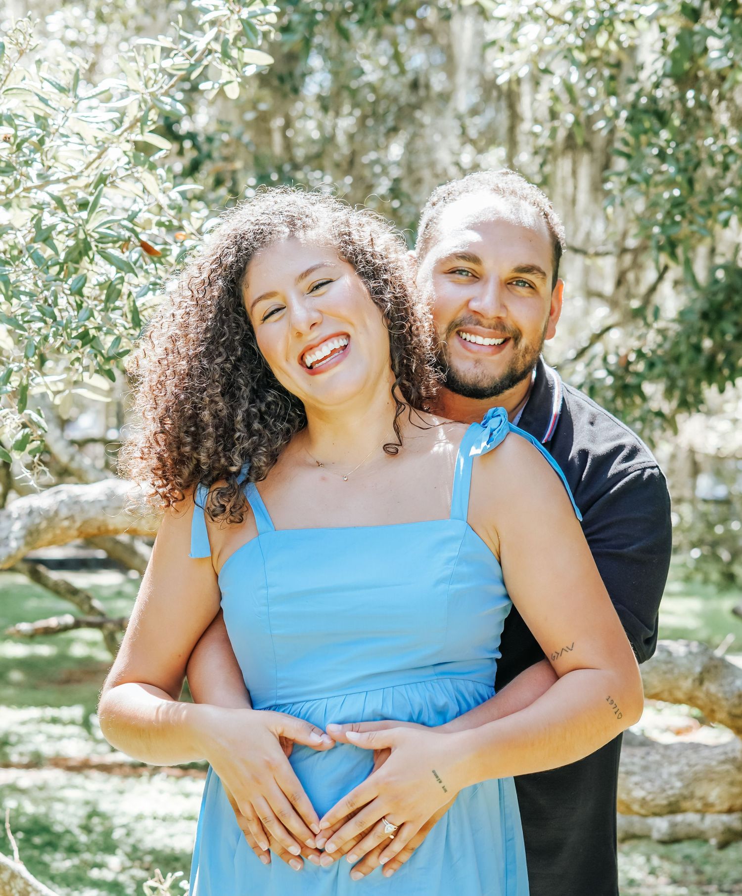 A couple embracing and laughing together in a sunny outdoor setting.