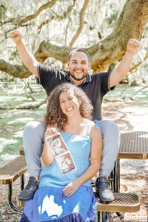 A couple celebrating with excitement while sitting on a park bench.