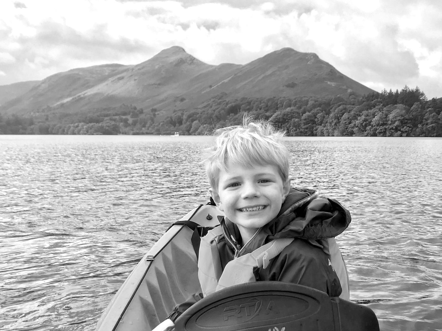 Theo smiling in a kayak on Derwentwater, with Catbells in the background.
