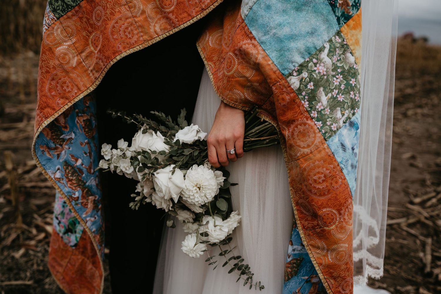 bride holding bouquet with blanket wrapped around her