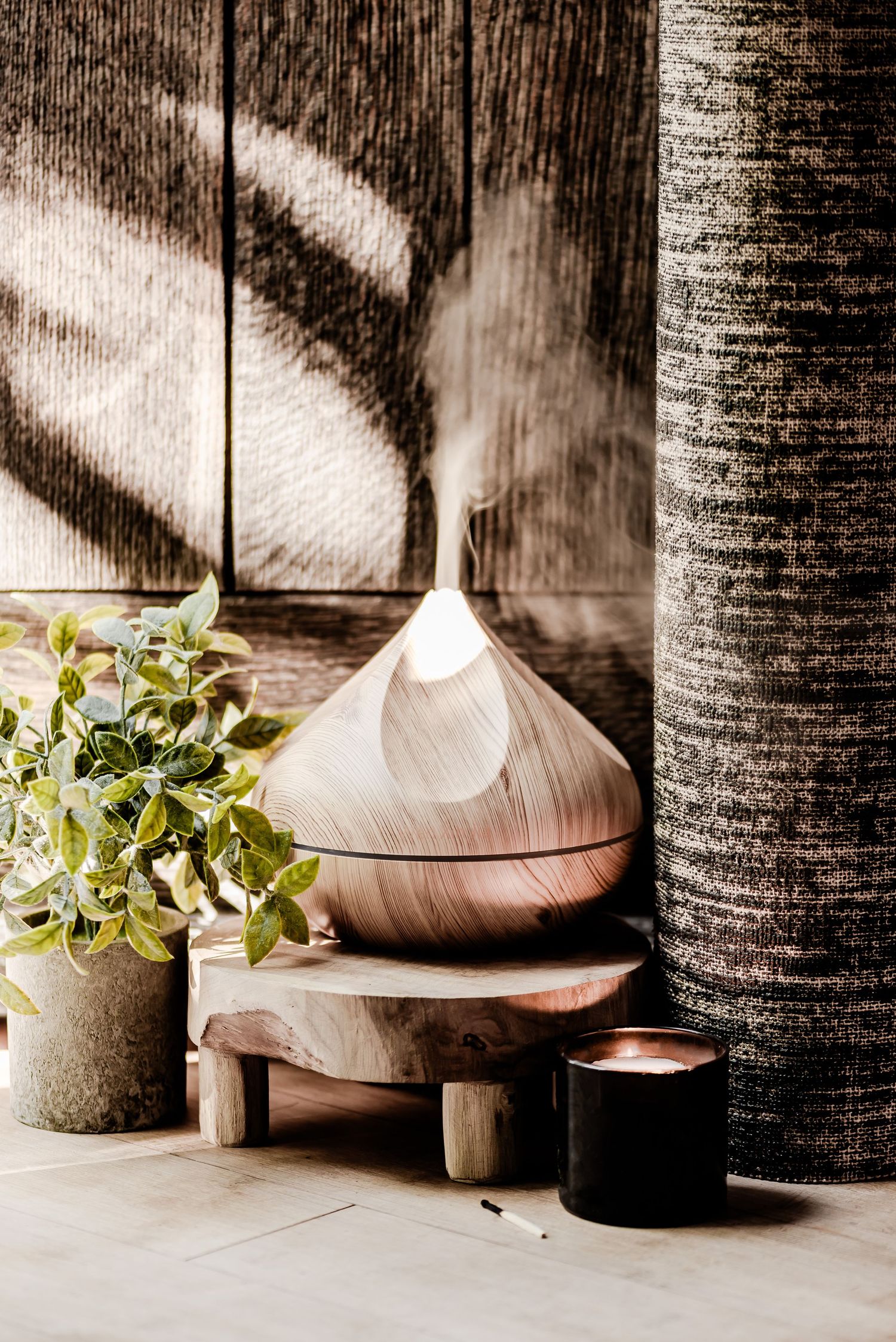 Diffuser and yoga mat next to a plant and an open door with sun streaming through. Healthy living, mindfulness