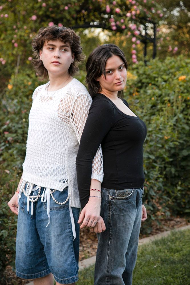 twin brother and sister back to back with arms intertwined looking somber