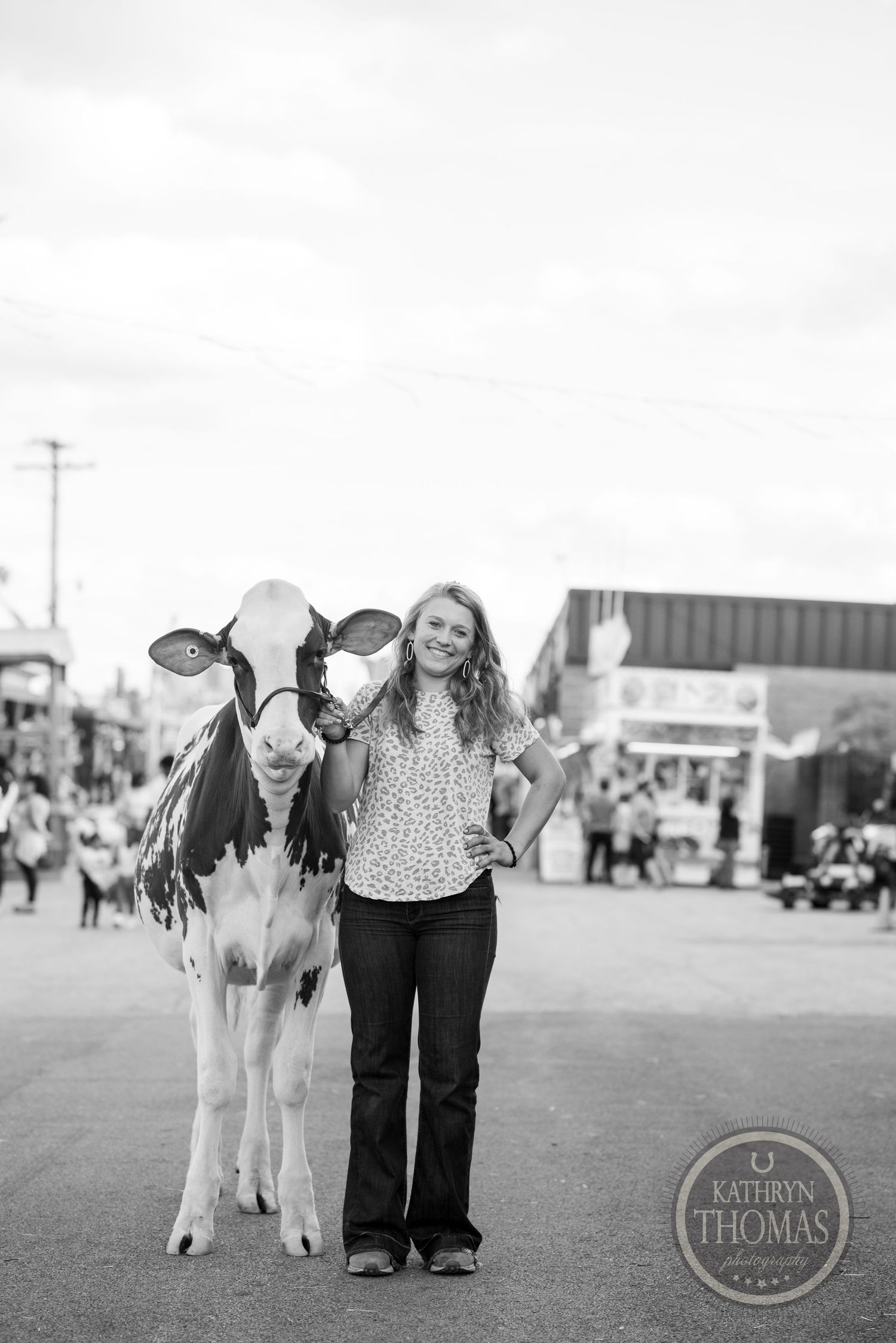 A black and white portrait of a young exhibitor with their dairy cow at a fair.