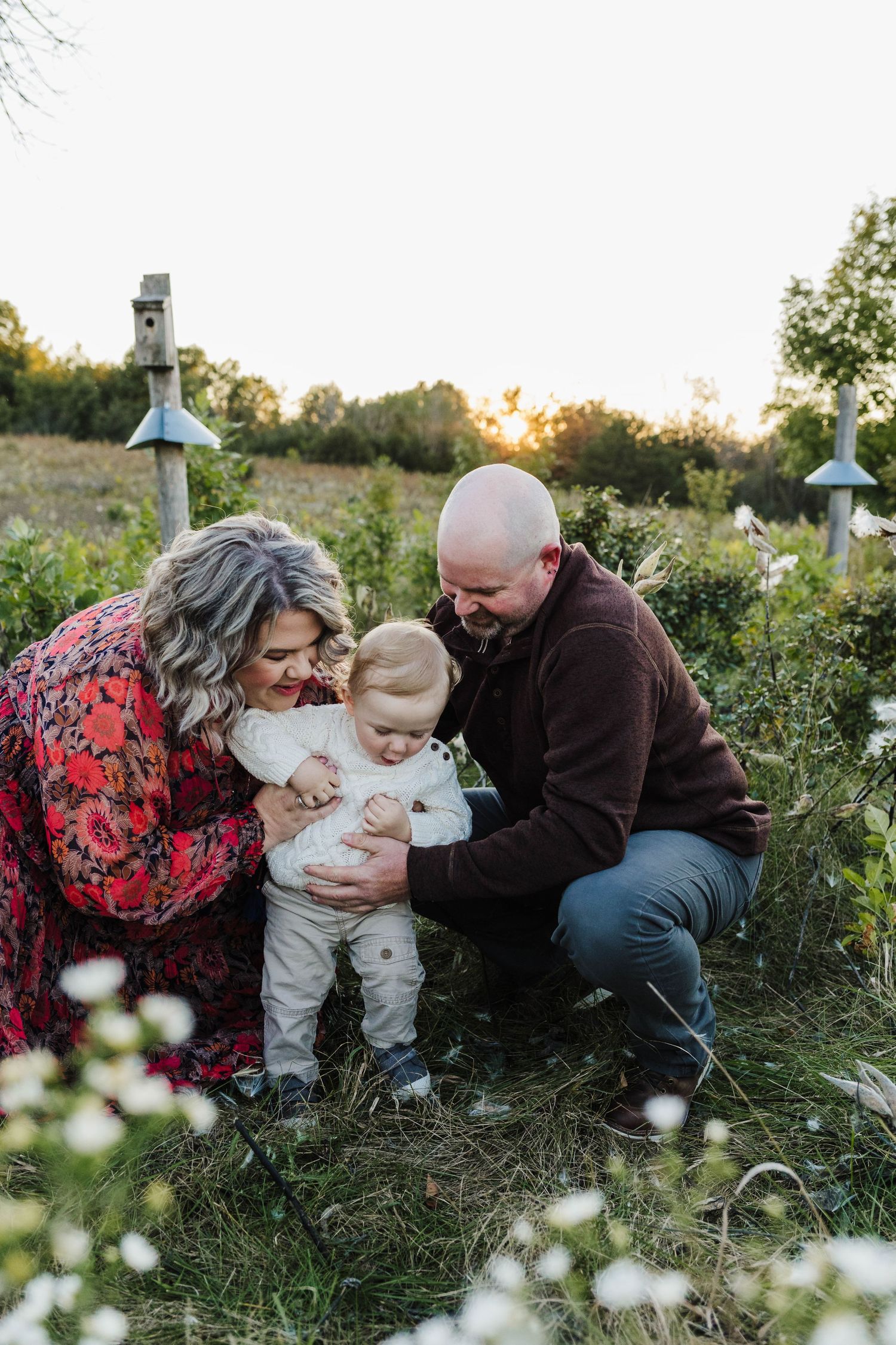 Family knees down to take photos of them and little one year old with lake country area photographer hartland , WI.