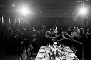 Black and white photo of wedding guests dancing together at elegant reception.