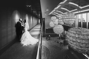 Black and white split image of bride and groom embracing in a modern wedding venue hallway.
