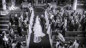 Aerial black and white view of bride walking down church aisle with wedding guests watching.