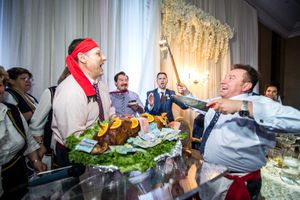 Lively wedding reception with guests in traditional costumes celebrating around a festive table.