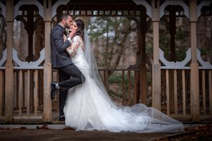 Bride and groom share romantic kiss on decorative wooden gazebo in autumn wedding portrait.