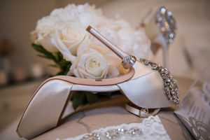Elegant bridal heels with crystal embellishments displayed beside white rose wedding bouquet.