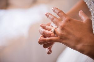 Close-up of bride placing wedding ring on finger during wedding ceremony.
