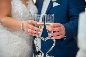 Bride and groom toast with engraved champagne flutes on heart-shaped silver stand.